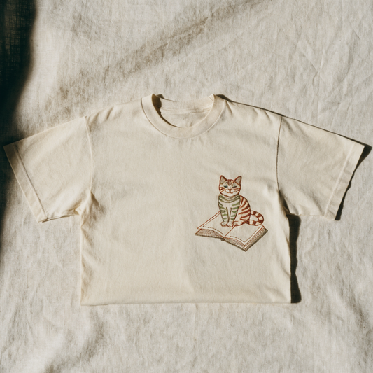 Cream cotton t-shirt with a cat sitting on a notebook embroidered on the left chest